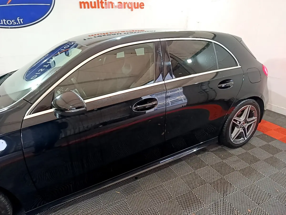 Profil côté gauche d'une Mercedes Classe A 180 AMG Line noire, soulignant ses jantes sport et ses lignes élégantes.