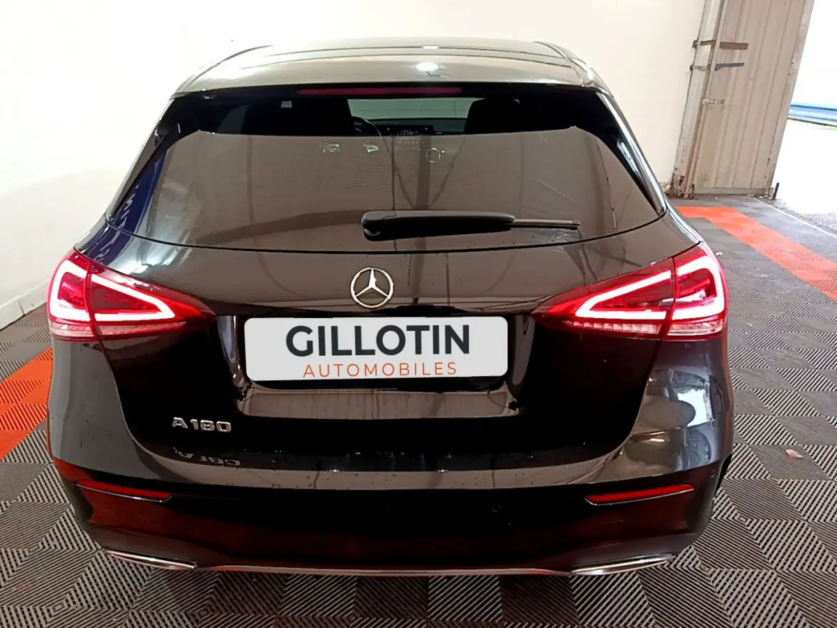 Vue arrière d'une Mercedes Classe A 180 AMG Line noire avec feux LED allumés dans un garage.