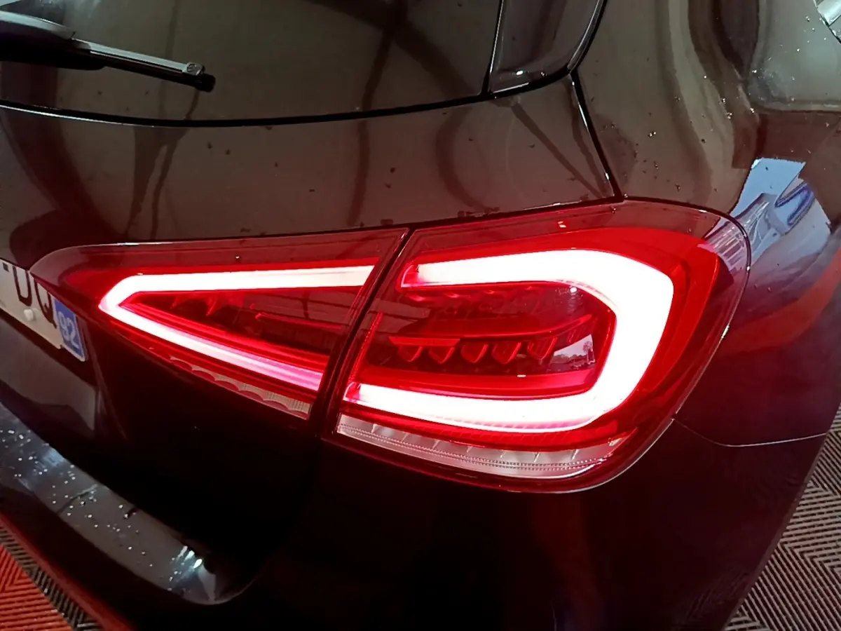 Feu arrière droit allumé d'une Mercedes Classe A 180 AMG Line noire vue en gros plan sur l'arrière.