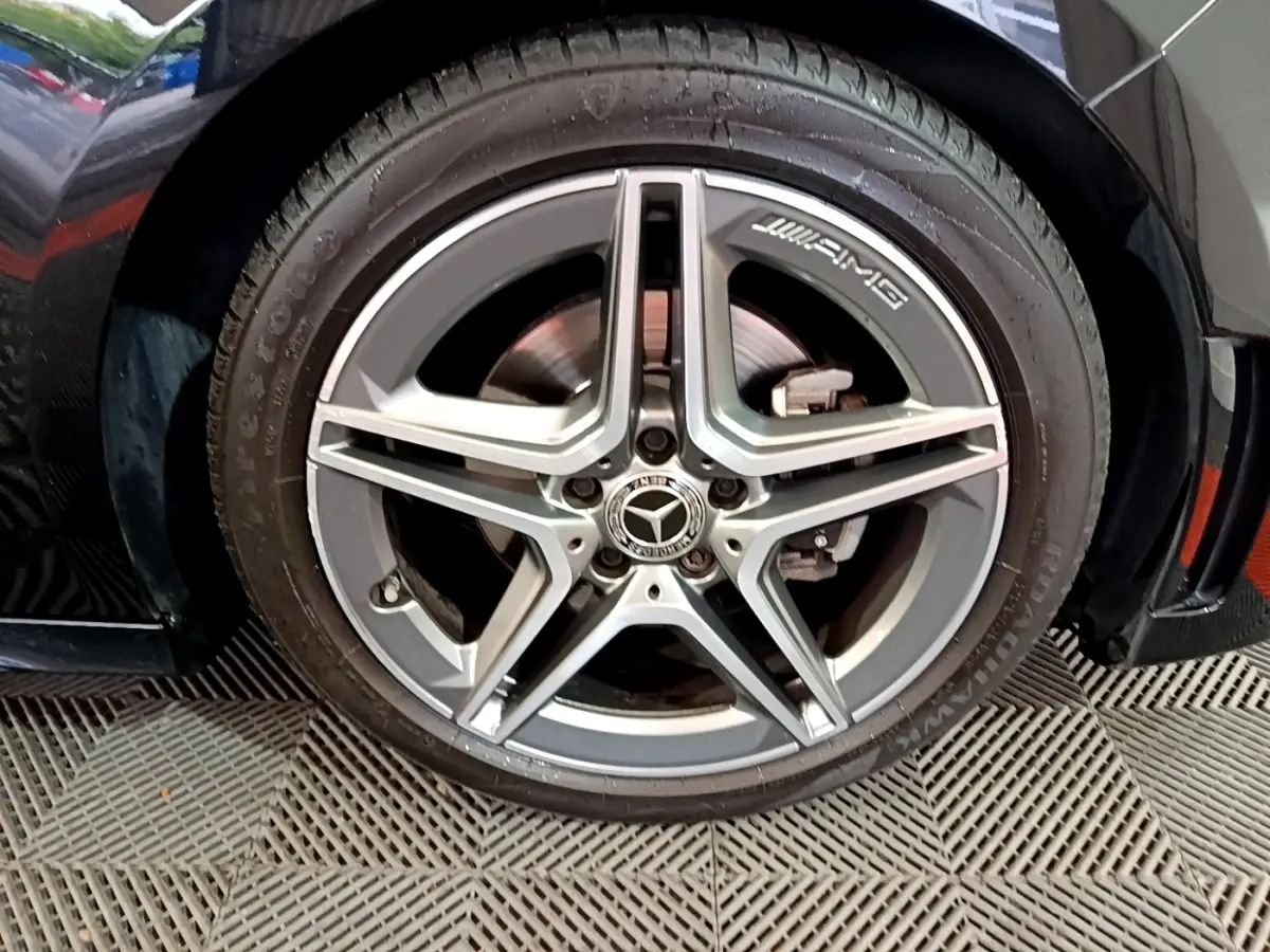 Gros plan sur la roue avant droite noire d'une Mercedes Classe A 180 AMG Line avec jante AMG argentée.