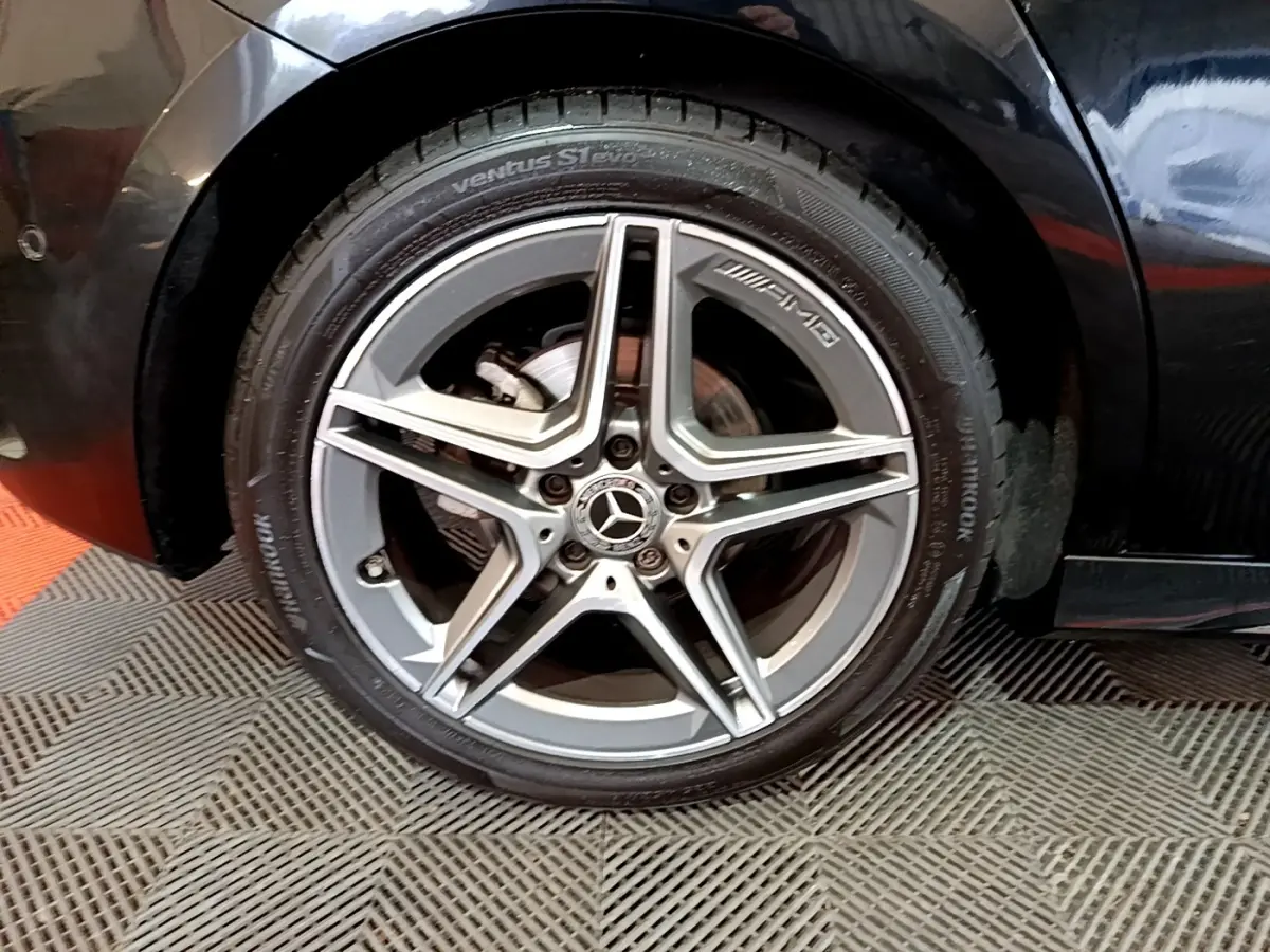 Gros plan sur la roue avant droite noire d'une Mercedes Classe A 180 AMG Line avec jante AMG argentée cinq branches