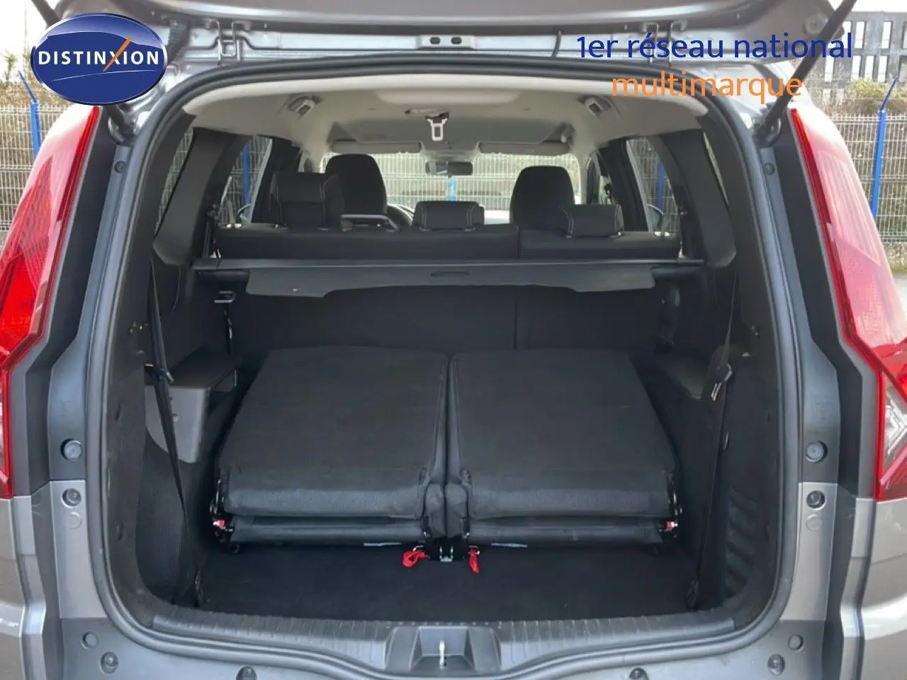 Vue arrière du coffre ouvert du Dacia Jogger gris schiste métal avec sièges rabattus et banquette arrière visible.