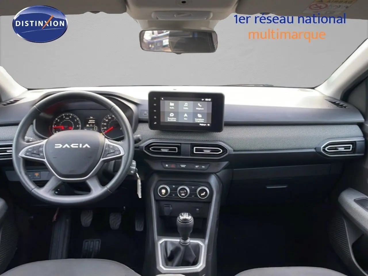 Vue intérieure frontale du tableau de bord gris et noir du Dacia Jogger 2025 avec écran tactile et boîte manuelle.