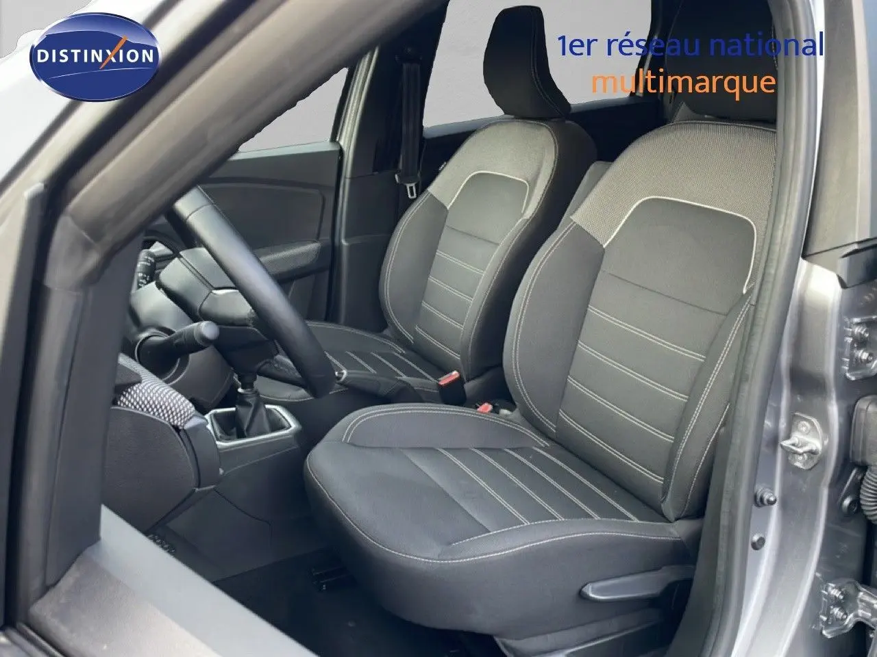 Vue intérieure côté conducteur du Dacia Jogger gris schiste métal, montrant les sièges avant en tissu noir et la boîte manuelle.