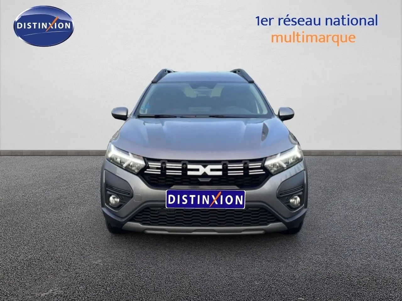 Vue de face du Dacia Jogger gris schiste métal 2025 avec calandre noire et feux LED allumés.