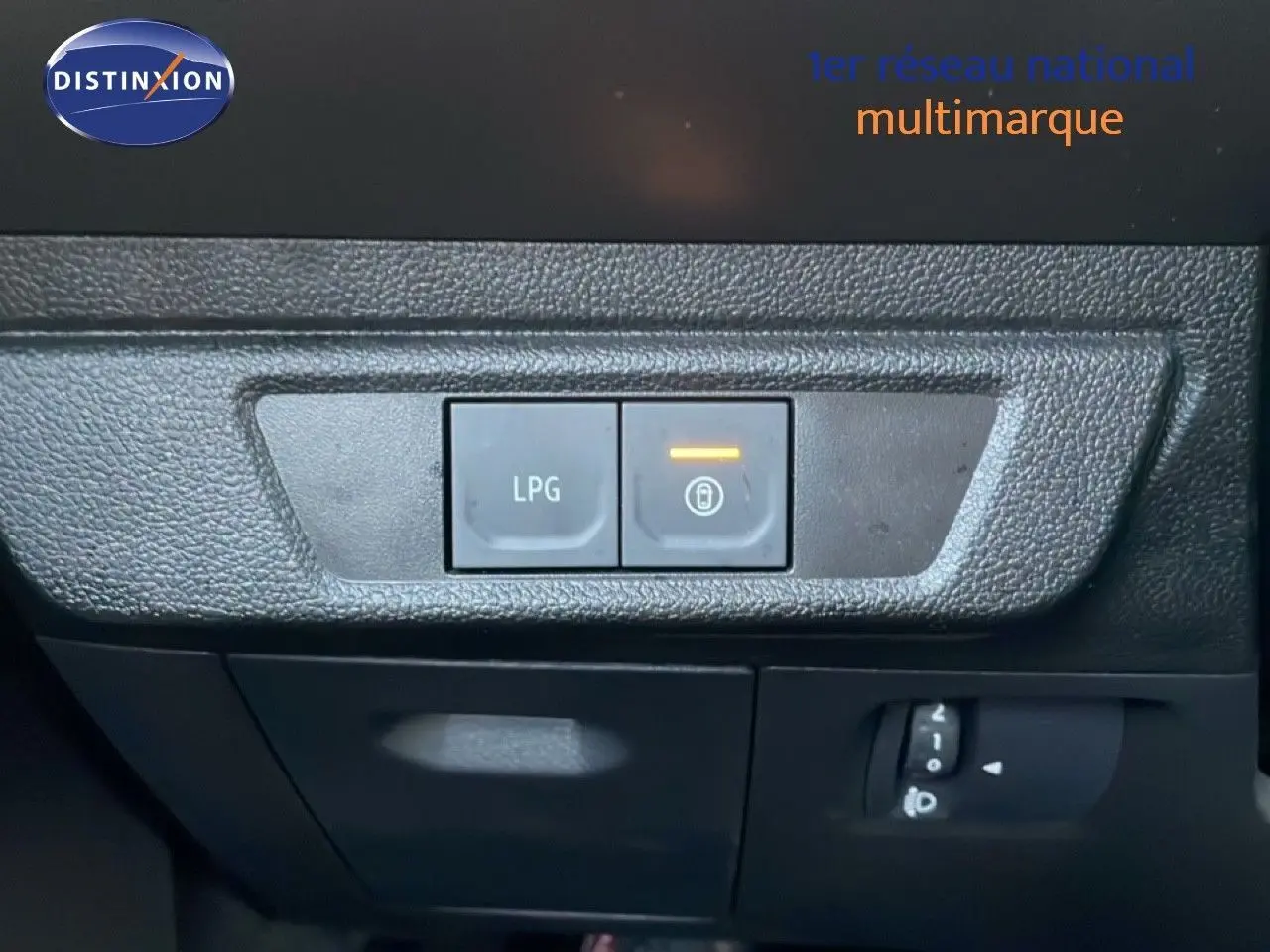 Gros plan sur les boutons de commande LPG et verrouillage intérieur du tableau de bord d’un Dacia Jogger gris schiste métal.