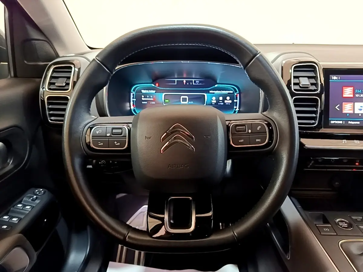 Vue intérieure centrée sur le volant cuir noir multifonctions du Citroën C5 Aircross 2020 avec tableau de bord digital lumineux.