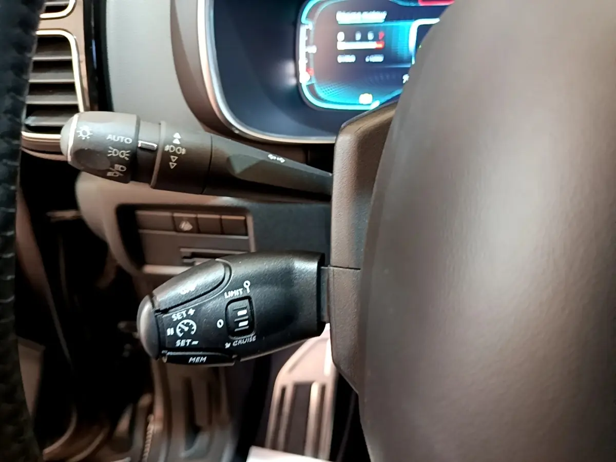 Gros plan sur les commandes du régulateur de vitesse et des feux, volant cuir gris foncé de Citroën C5 Aircross.