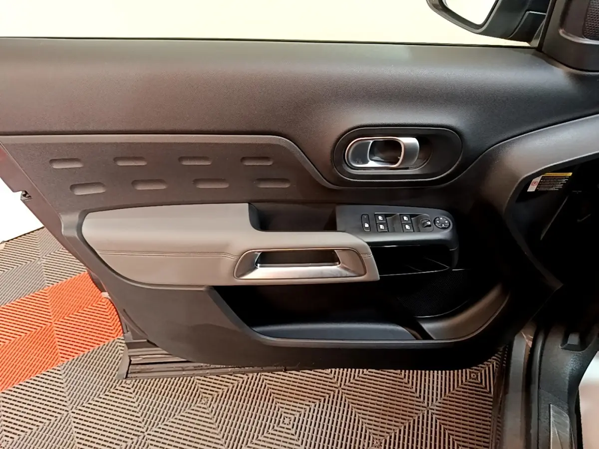 Vue intérieure côté gauche de la porte avant d'une Citroën C5 Aircross 2020 avec commandes de vitres et poignée argentée.