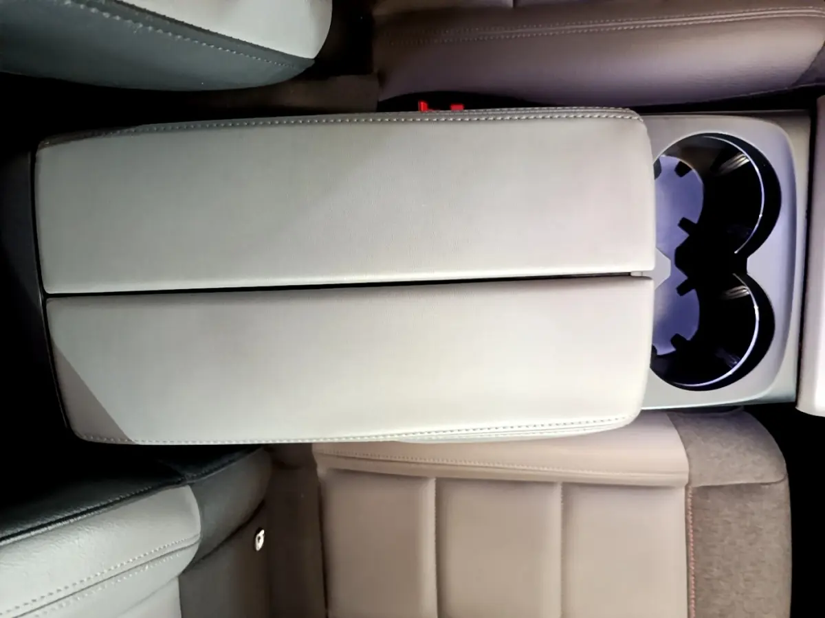 Vue plongeante sur l'accoudoir central beige et les porte-gobelets du siège arrière du Citroën C5 Aircross gris foncé.