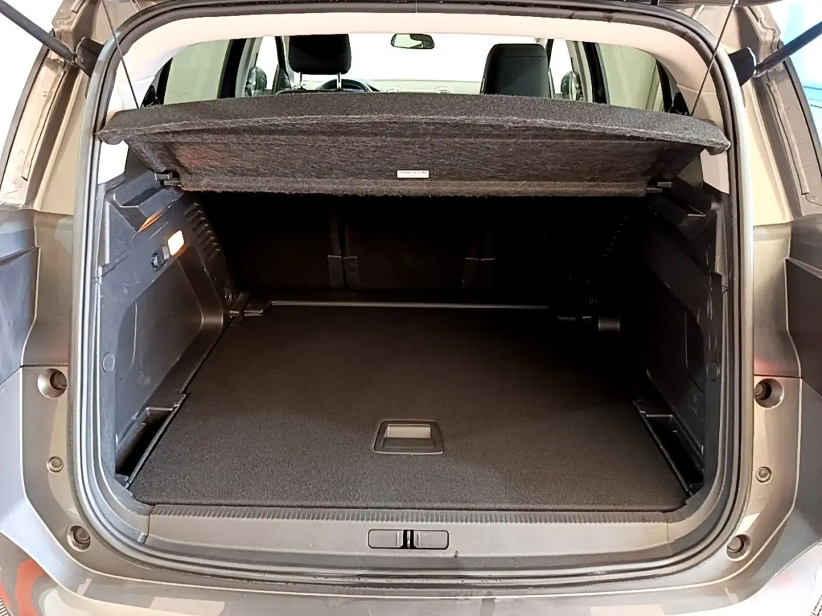 Coffre ouvert vu de l'arrière d'un Citroën C5 Aircross gris foncé, avec cache-bagages relevé et intérieur spacieux.