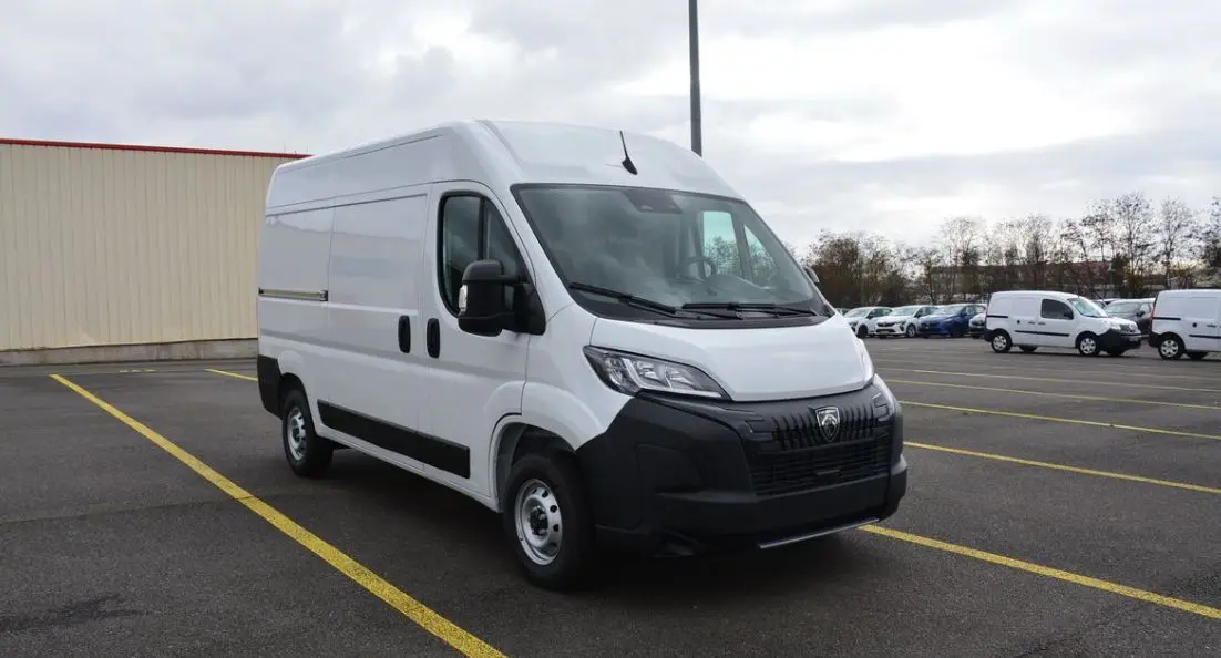Peugeot Boxer Fourgon blanc Icy vu en 3/4 avant droit sur parking, avec calandre noire et rétroviseurs noirs.