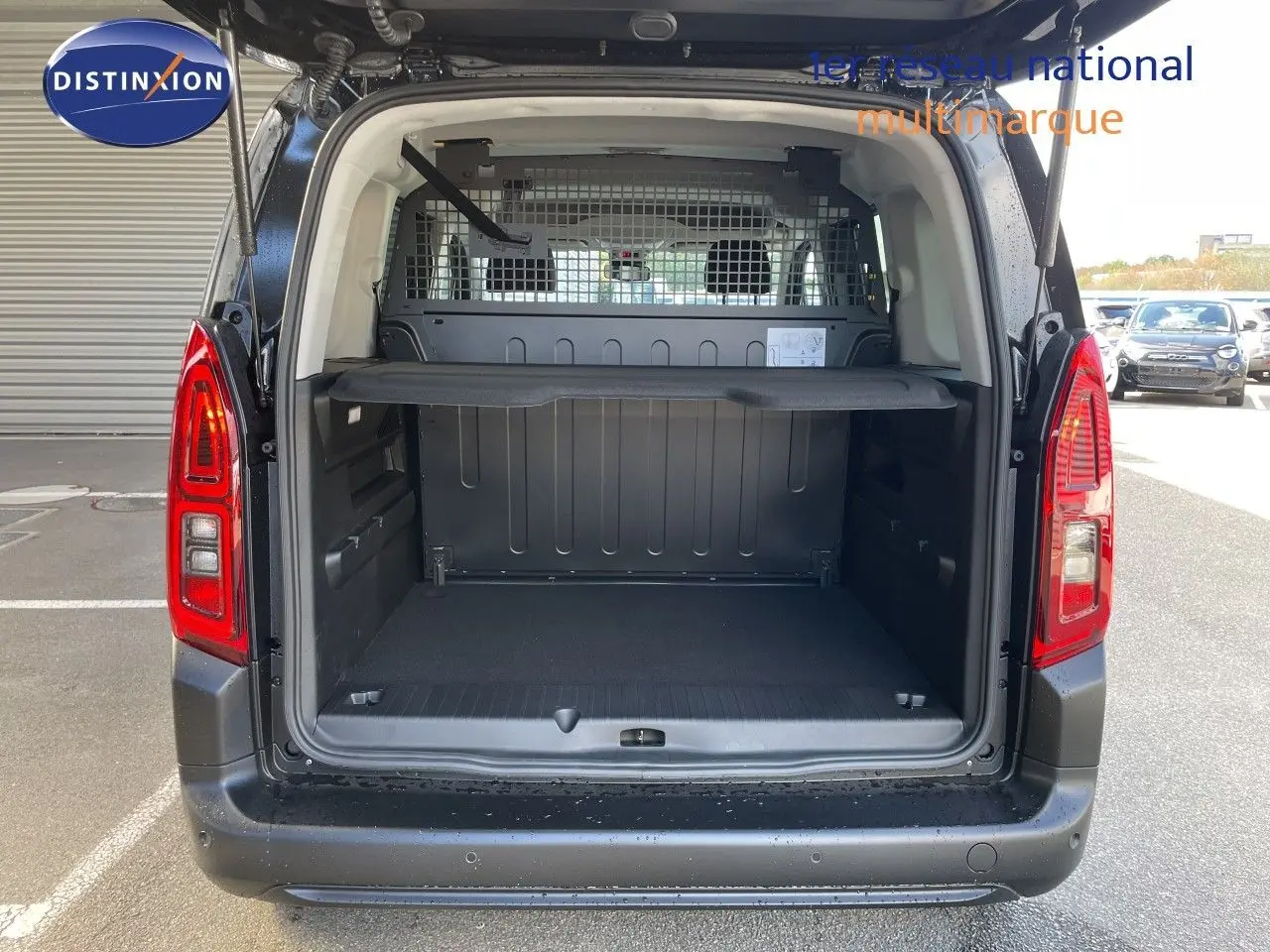 Coffre ouvert en vue arrière d'un Citroën Berlingo noir Perla Nera, montrant l'espace de chargement et la grille de séparation.