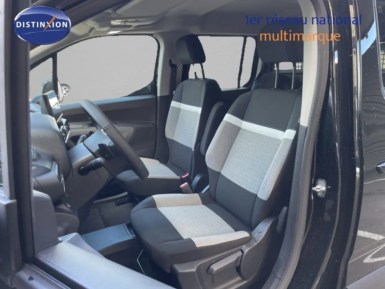 Vue intérieure côté conducteur du Citroën Berlingo noir Perla Nera, sièges tissu bicolore gris et noir visibles.