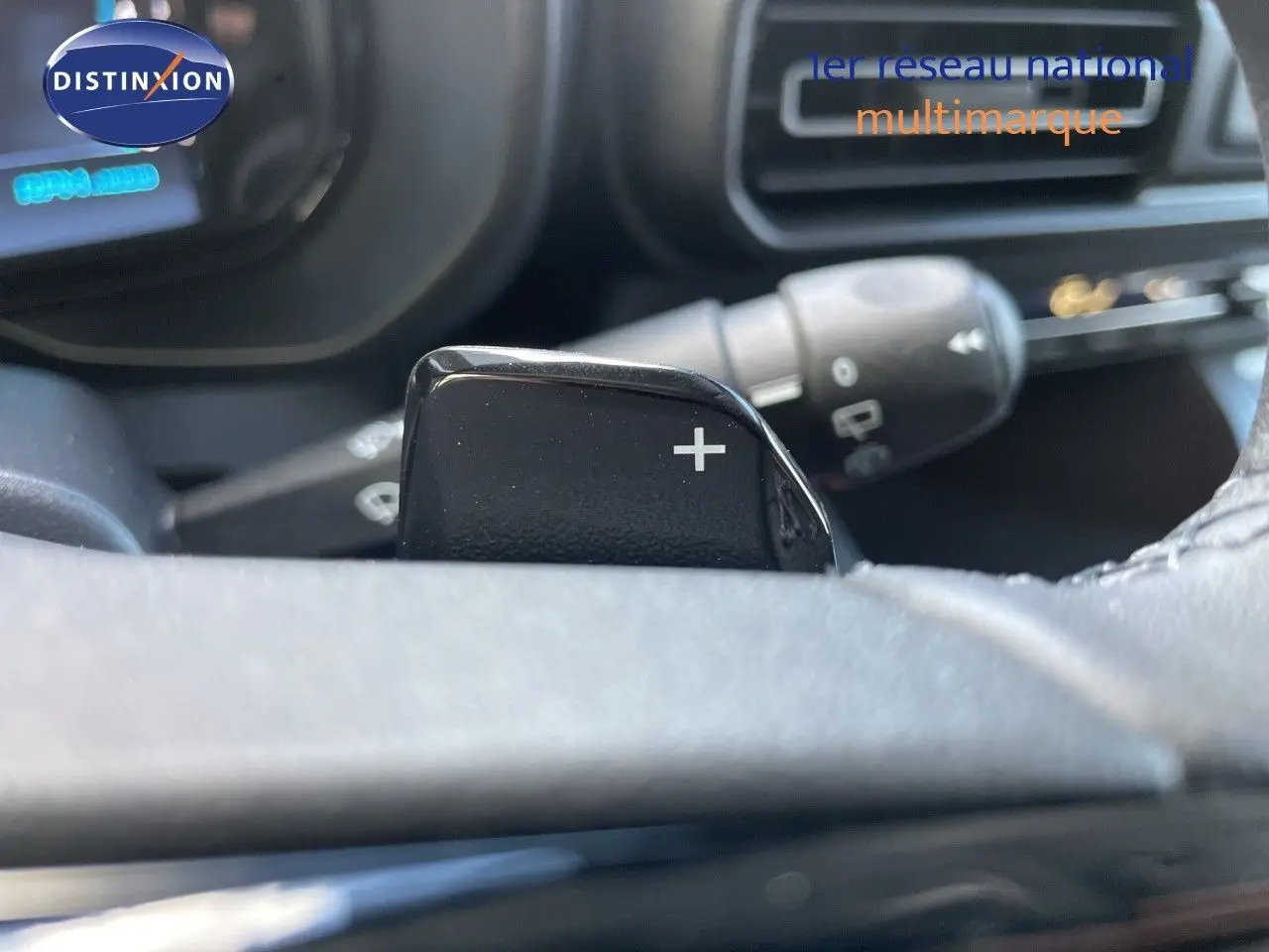 Gros plan sur la palette de changement de vitesse "+" du volant d'un Citroën Berlingo noir Perla Nera, intérieur sombre.
