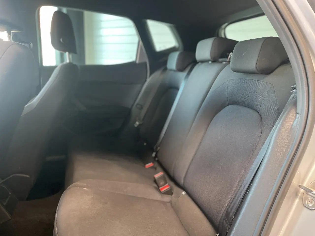 Vue intérieure côté droit montrant la banquette arrière noire textile du SEAT Arona 2024 avec appuie-têtes et ceintures de sécurité.