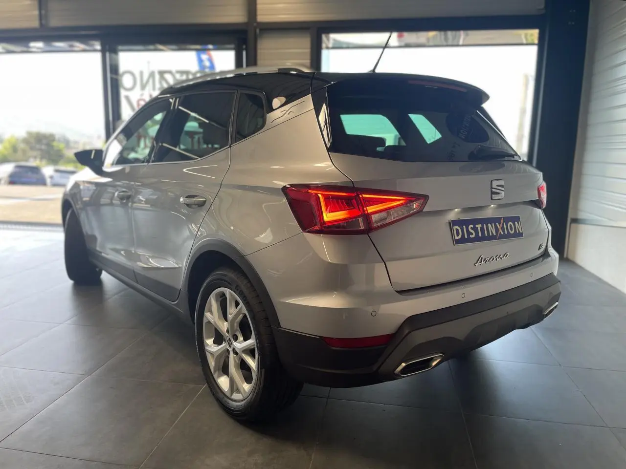 Vue 3/4 arrière droite d'une SEAT Arona 2024 rouge GRS avec feux allumés et jantes alliage 16 pouces.