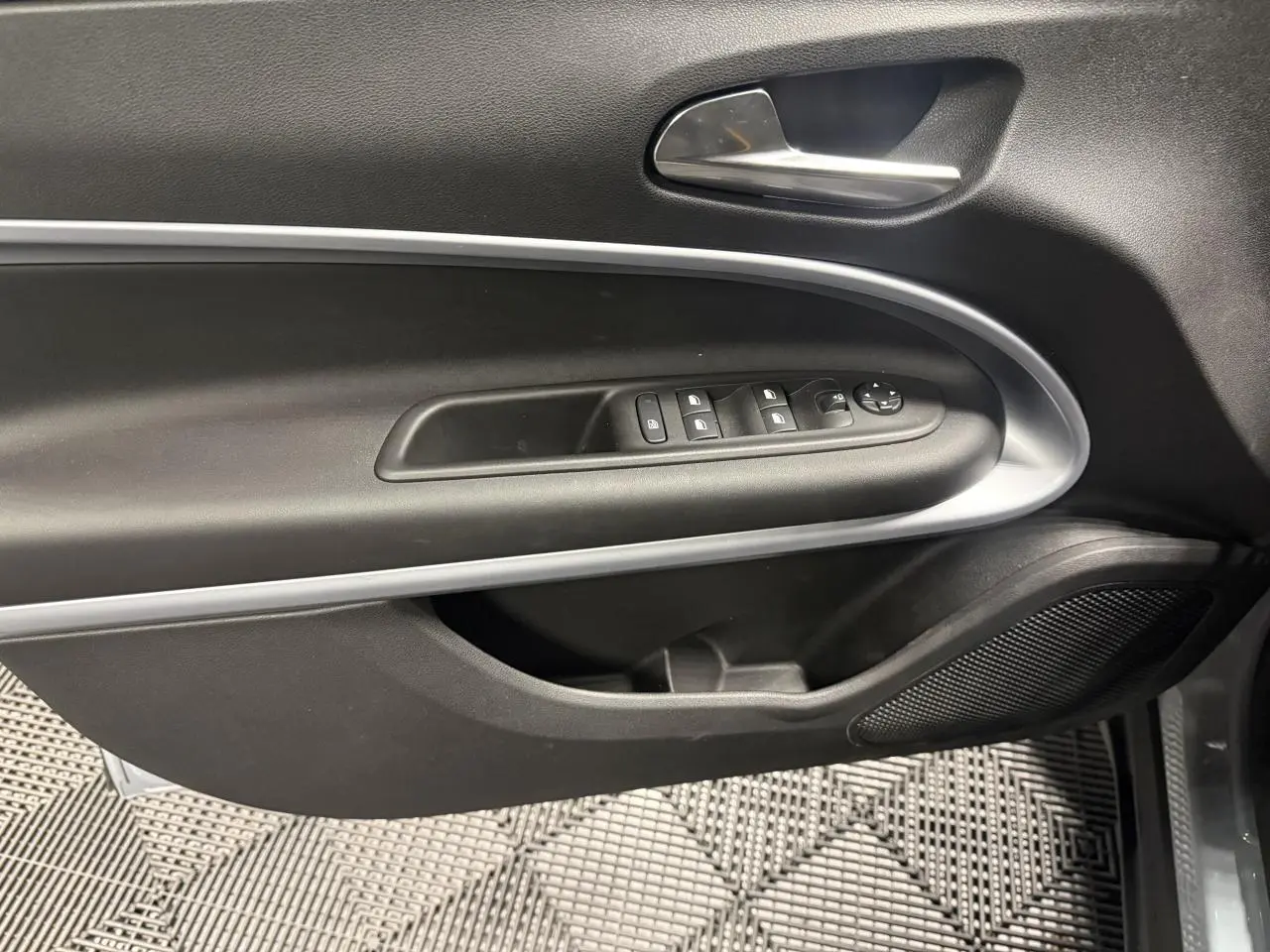 Vue intérieure du panneau de porte avant gauche gris foncé avec commandes électriques et poignée chromée du Jeep Avenger Hybrid 2026.