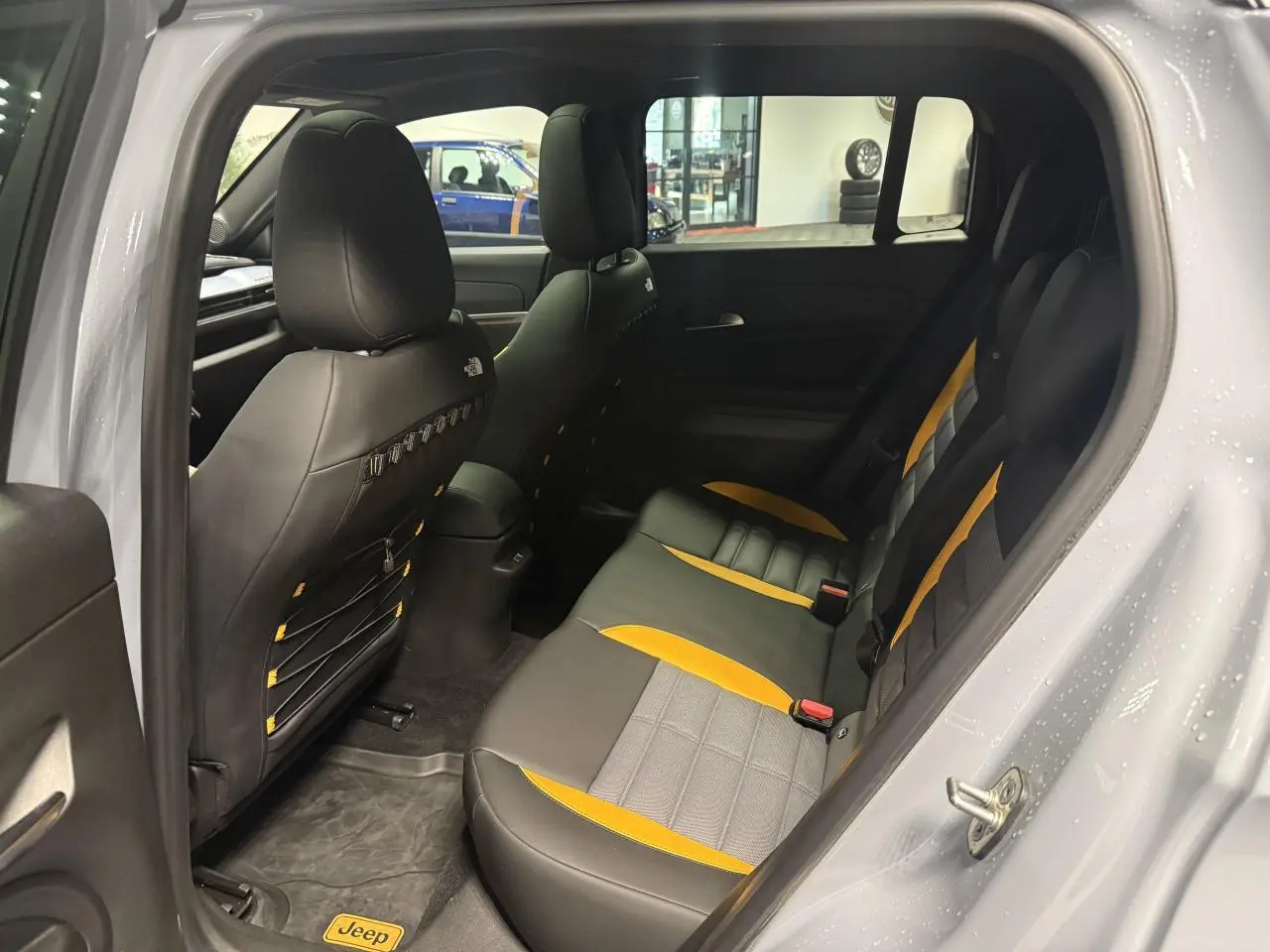 Vue intérieure côté gauche montrant la banquette arrière bicolore noire et jaune du Jeep Avenger Hybrid 4xe gris avec logo The North Face.