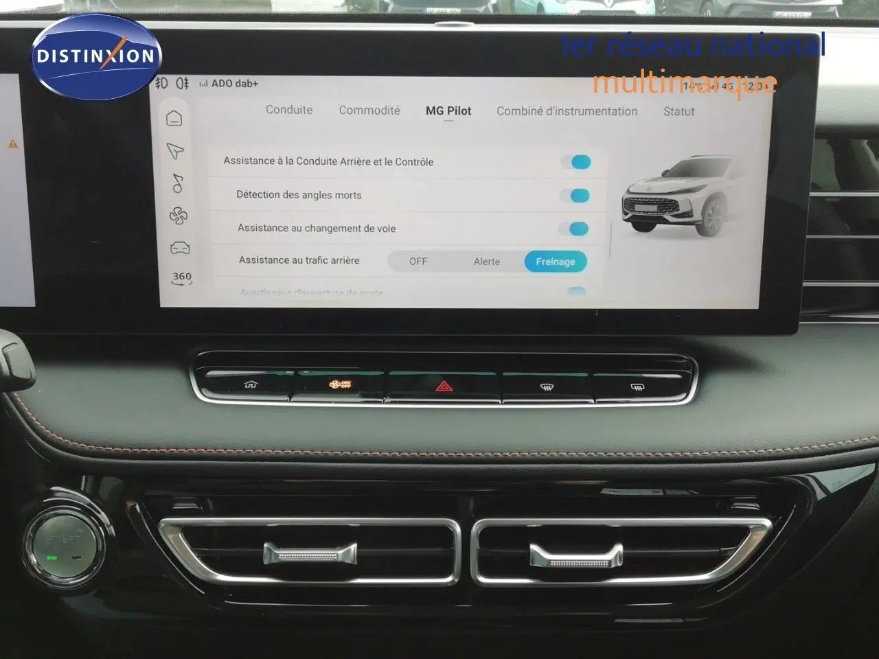 Vue rapprochée de l’écran tactile central et de la console noire du MG MOTOR EHS 1.5T PHEV 272CH LUXURY blanc perle, affichant les assistances à la conduite.