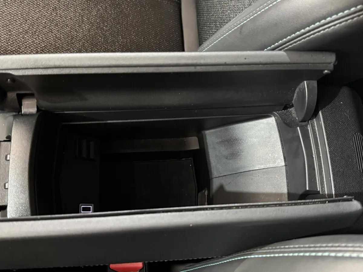 Vue plongeante sur le rangement central ouvert de la Peugeot 308 bleu, avec port USB visible à l'intérieur.