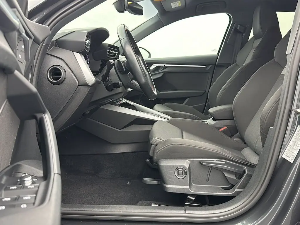Vue intérieure côté conducteur de l'Audi A3 Sportback 2021 gris Manhattan, montrant sièges et tableau de bord modernes.
