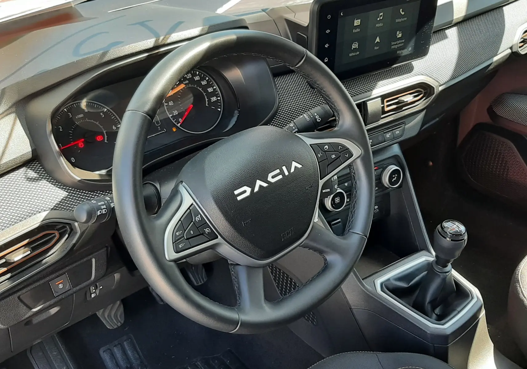 Vue intérieure côté conducteur de la Dacia Sandero Stepway 2025, volant multifonction, tableau de bord et écran tactile central.