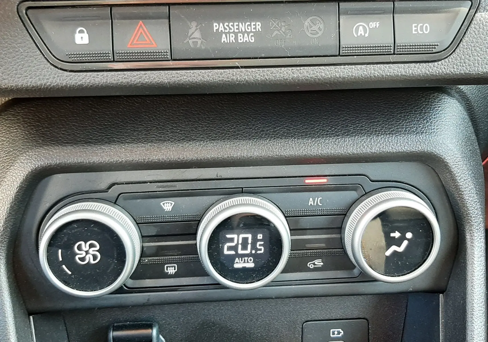 Détail de la console centrale de la Dacia Sandero Stepway 2025, montrant les commandes de climatisation et les boutons de sécurité.