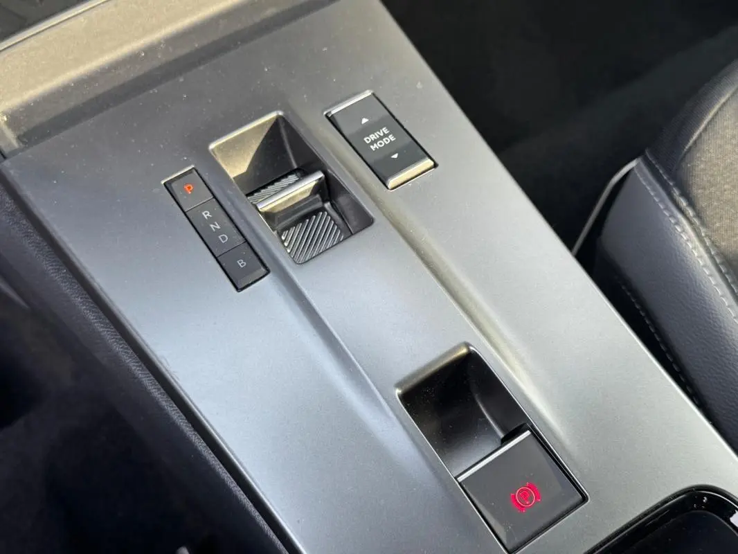 Gros plan sur la console centrale grise de l’Opel Mokka électrique 2025, montrant la commande de boîte auto et le bouton Drive Mode.