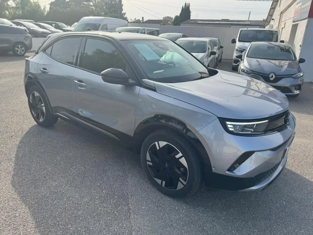 Opel Mokka électrique gris en 3/4 avant droit, avec jantes alliage noires et vitres surteintées.