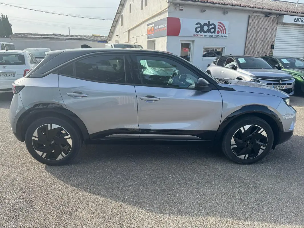 Vue de profil côté gauche d’un Opel Mokka électrique gris 2025 avec jantes alliage 17 pouces et vitres surteintées.
