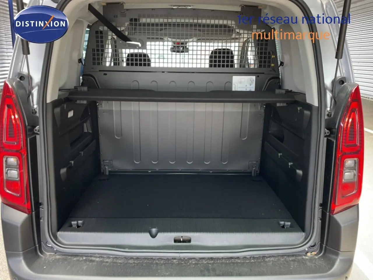 Vue arrière du Citroën Berlingo gris Artense métal 2026, coffre ouvert avec séparation grillagée et espace de chargement vide.