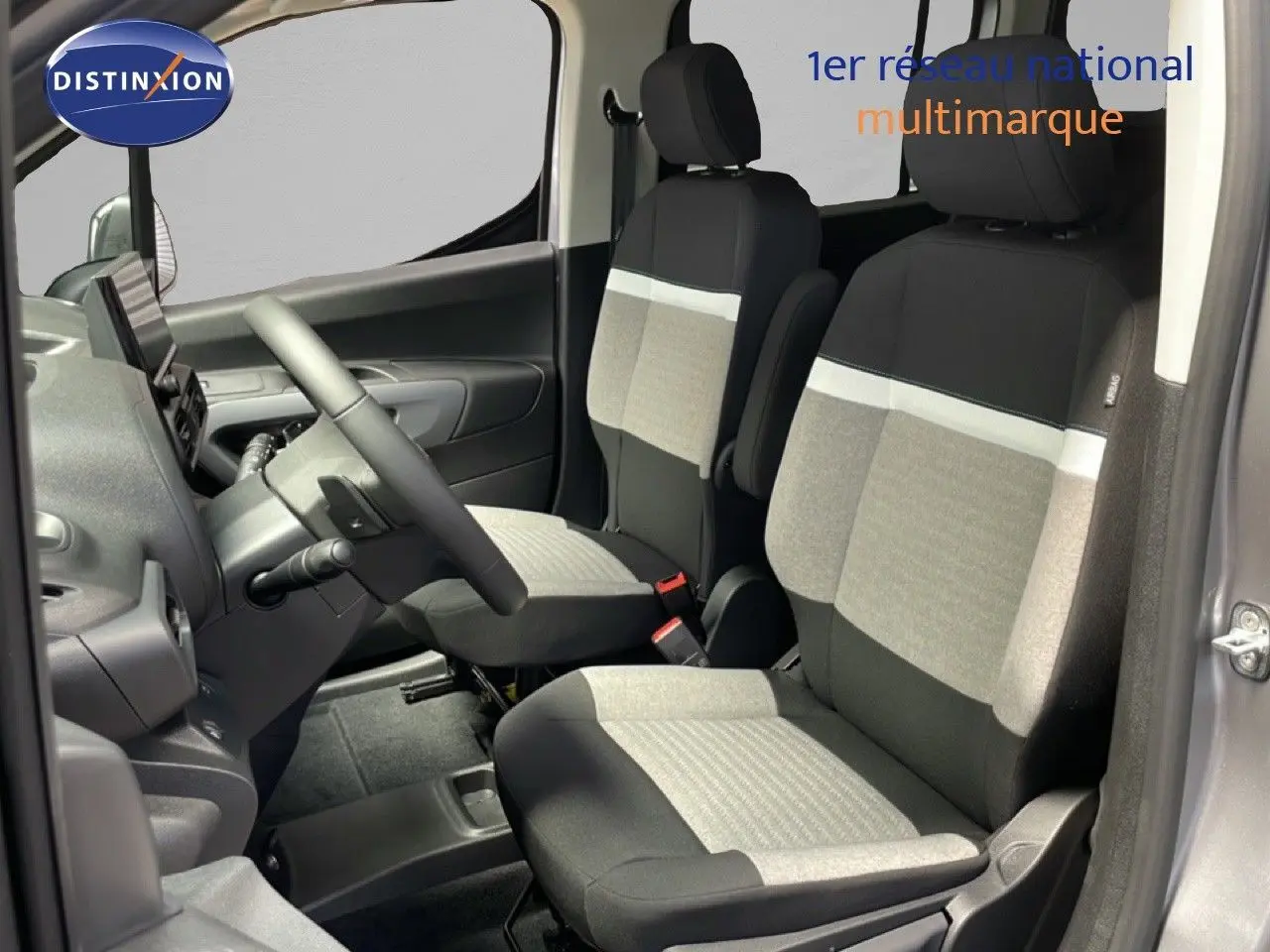 Vue intérieure côté conducteur du Citroën Berlingo gris Artense, sièges tissu bicolores avec bande blanche distinctive.