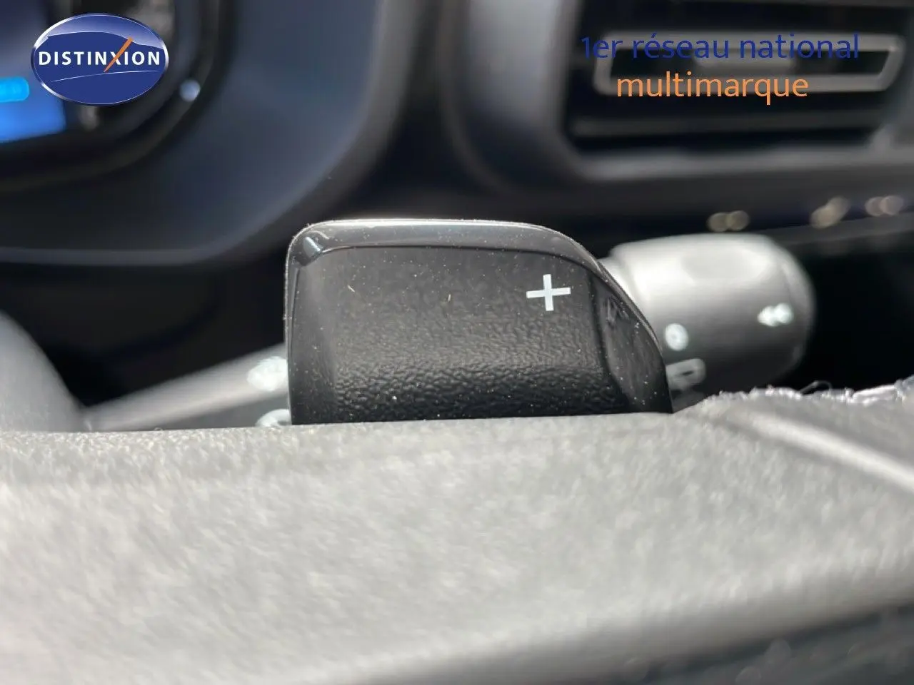 Gros plan sur la palette de changement de vitesse + au volant cuir du Citroën Berlingo gris Artense 2026, intérieur noir.