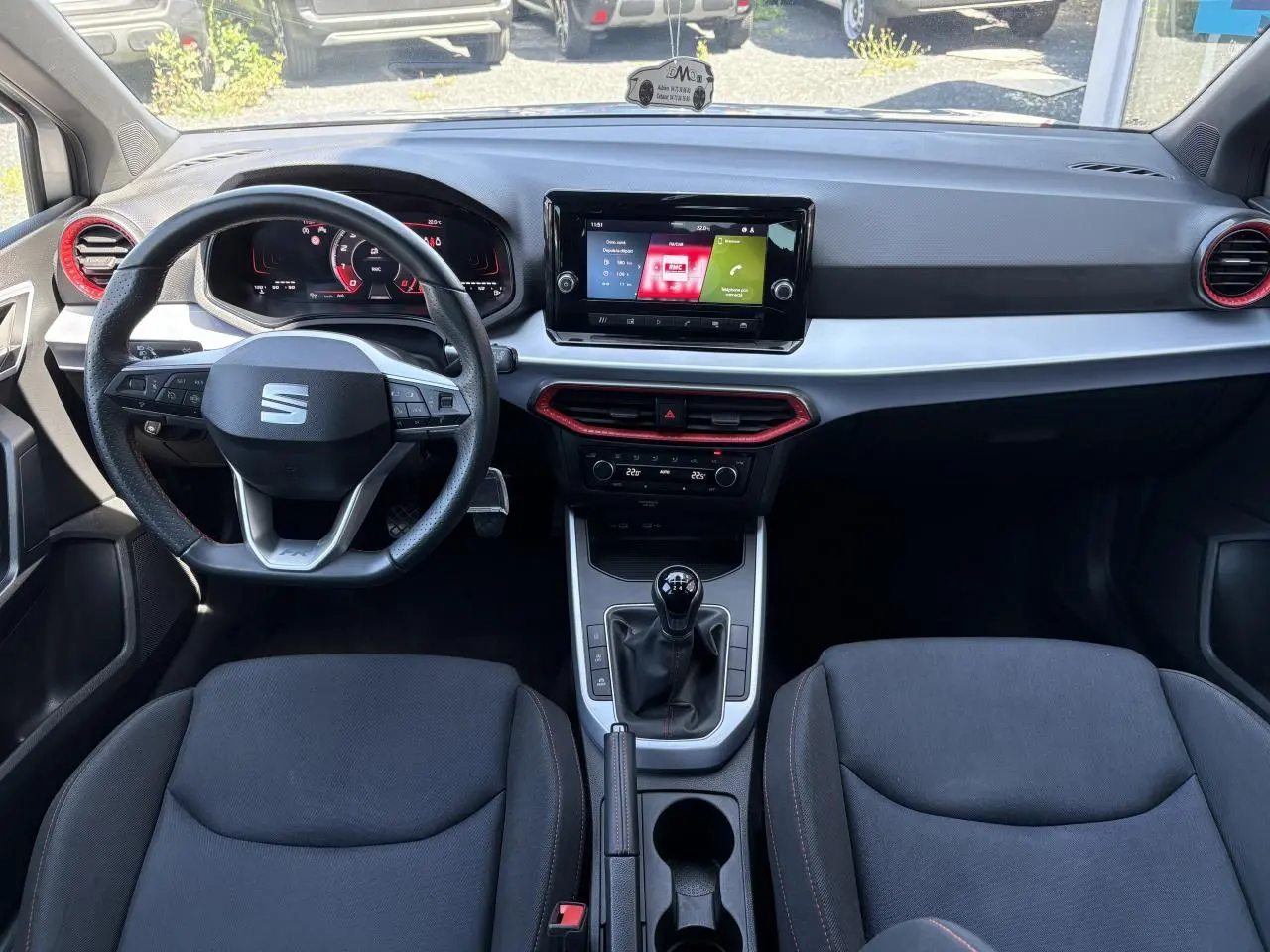 Vue intérieure avant du SEAT Arona 2024 avec volant sport cuir, écran tactile 8,25 pouces et sellerie textile noire.