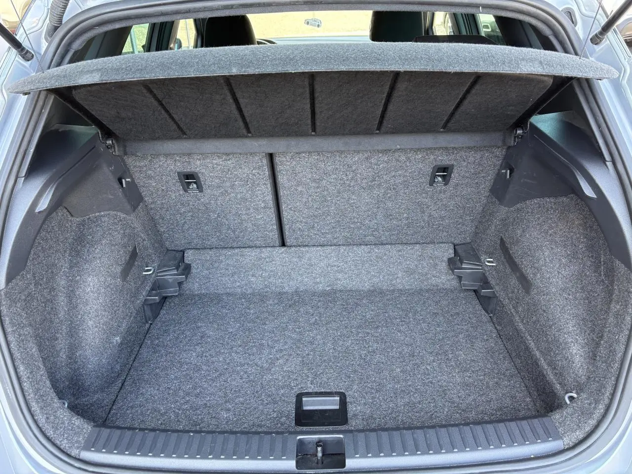 Coffre ouvert gris du SEAT Arona 2024, vue arrière montrant la banquette rabattable et le plancher à double fond.