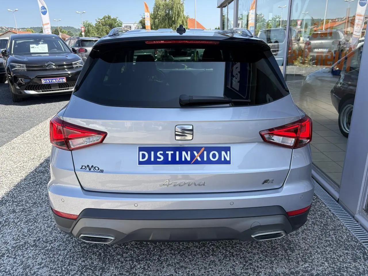 Vue arrière d'un SEAT Arona 2024 gris clair avec logos distinctifs et double sortie d'échappement intégrée.