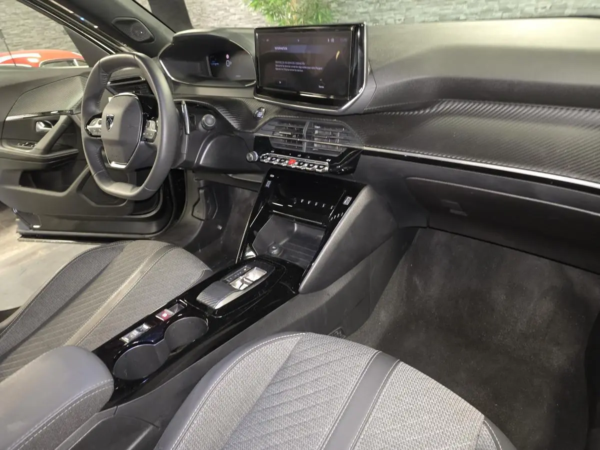Vue intérieure côté conducteur du Peugeot 2008 noir 2025, mettant en valeur le tableau de bord et la console centrale moderne.