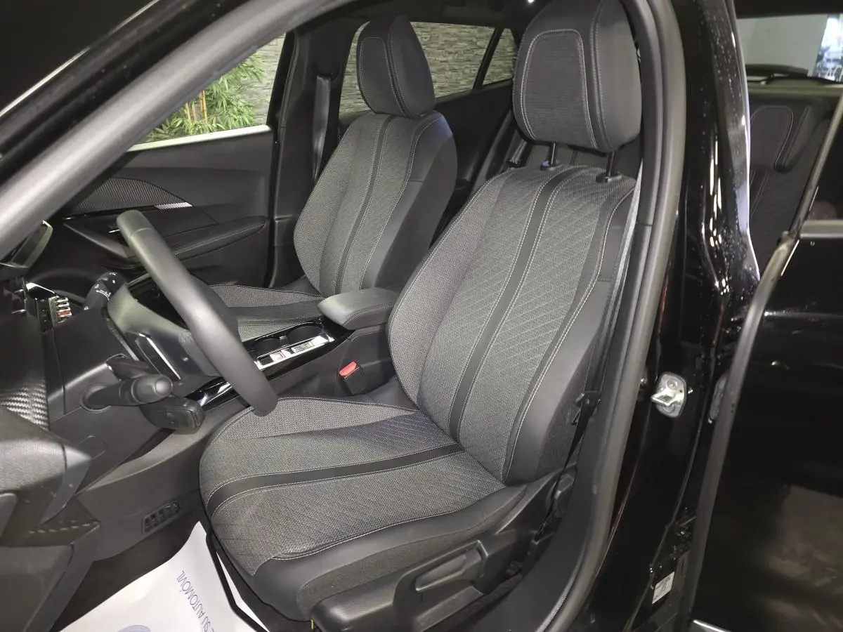 Vue intérieure côté conducteur de la Peugeot 2008 noire, mettant en valeur les sièges tissu et cuir avec surpiqûres Quartz.