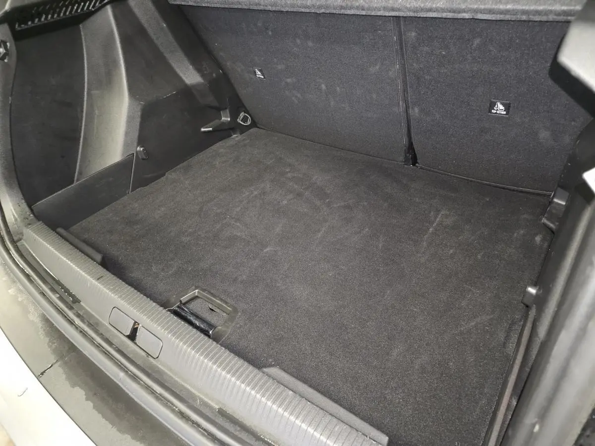 Vue intérieure du coffre noir du Peugeot 2008 1.2i Hybrid 2025, montrant la surface de chargement et les sièges arrière rabattus.