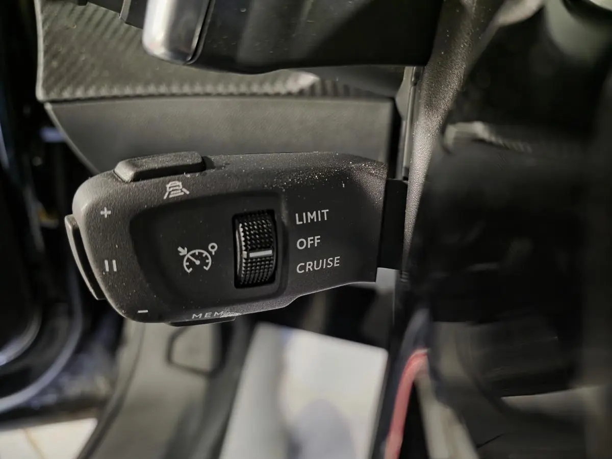 Gros plan sur la commande de régulateur de vitesse du Peugeot 2008 noir, côté gauche du volant.