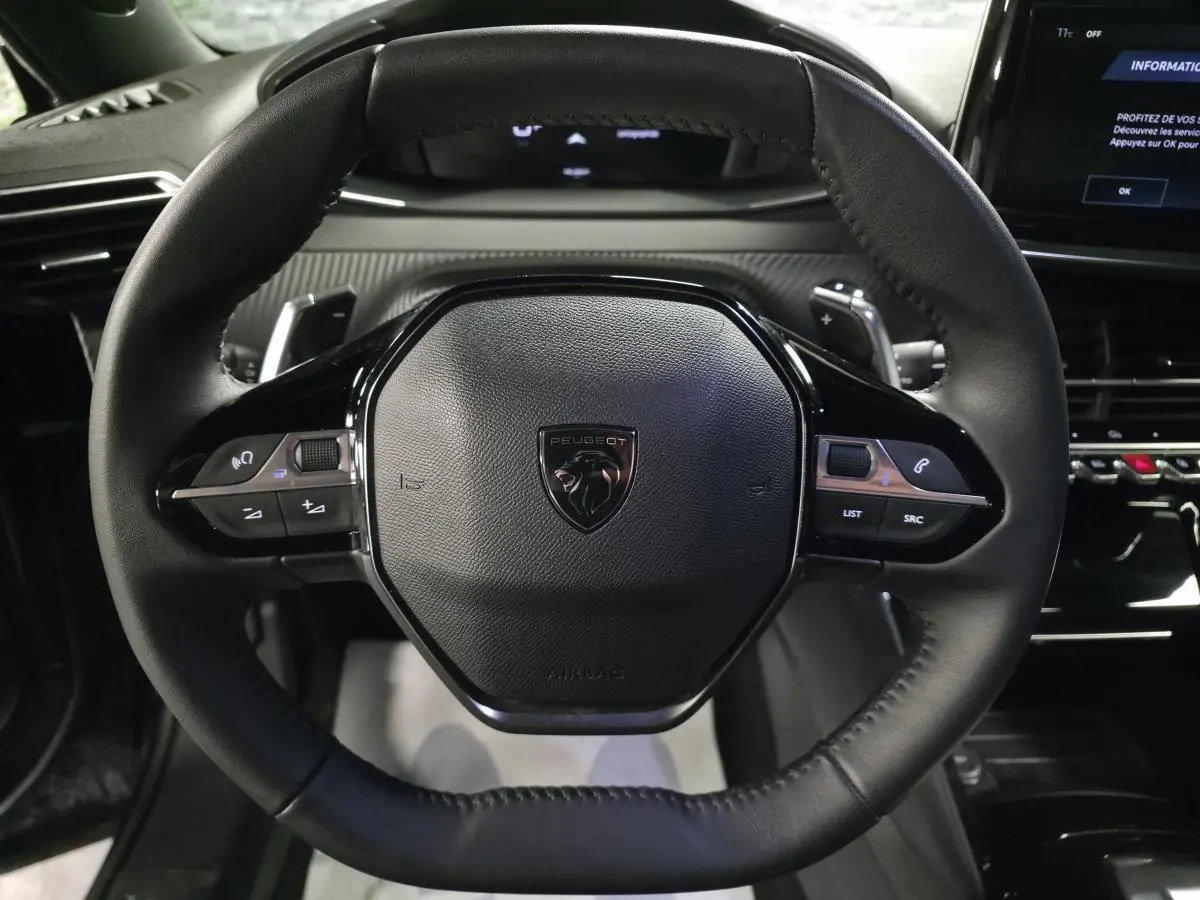 Vue rapprochée du volant compact en cuir noir avec commandes multimédia intégrées du Peugeot 2008 1.2i Hybrid 2025.