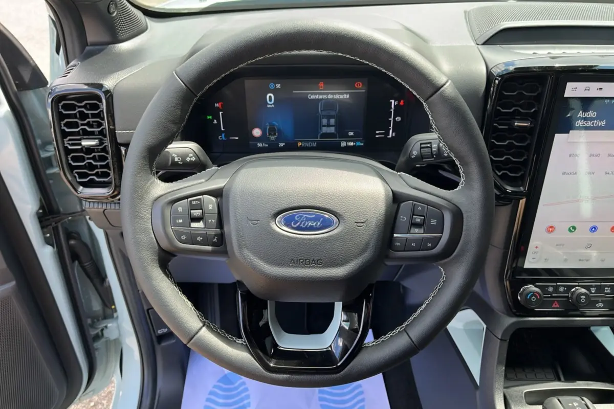 Vue rapprochée du volant cuir multifonctions du Ford Ranger gris zen avec tableau de bord digital et écran tactile.