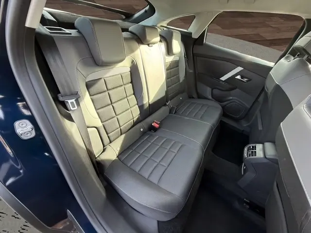 Vue intérieure arrière côté gauche de la Citroën C4 hybride 2025 bleu, banquette 3 places avec appuie-têtes et ceintures visibles.