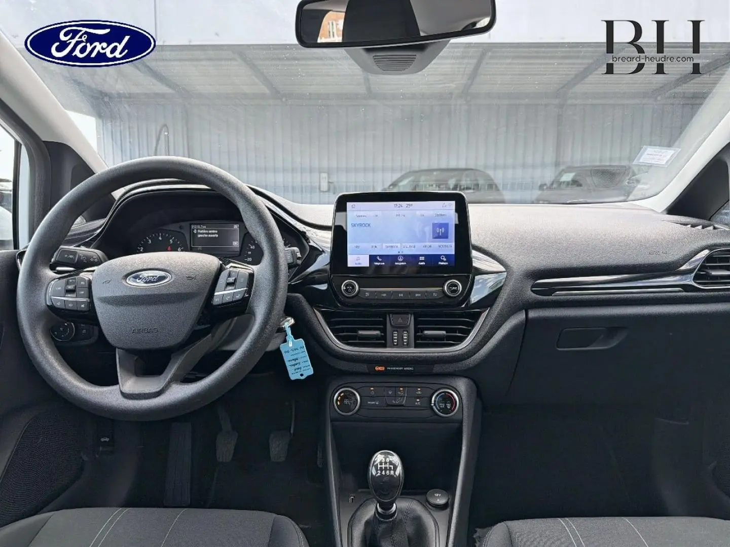 Vue intérieure avant de la Ford Fiesta 2020 avec tableau de bord noir, écran tactile central et levier de vitesses manuel.