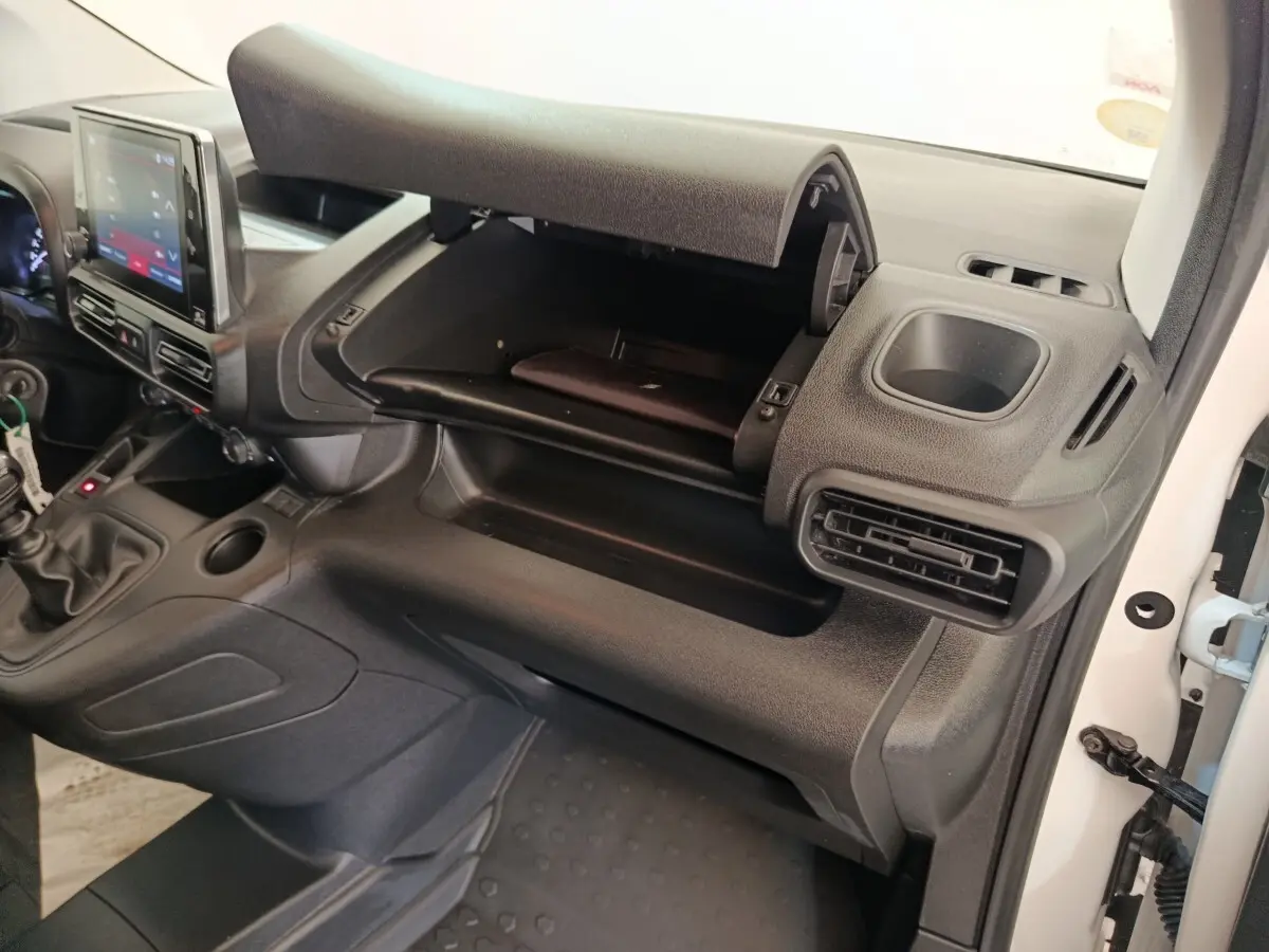 Intérieur du Citroën Berlingo 2022 blanc, vue côté passager sur la boîte à gants ouverte et tableau de bord noir.