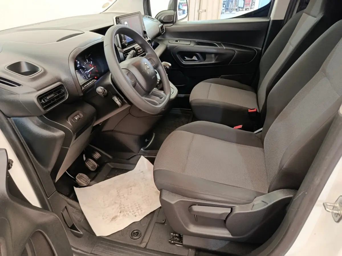 Vue intérieure côté conducteur du Citroën Berlingo blanc 2022, montrant le volant, les sièges et le tableau de bord.