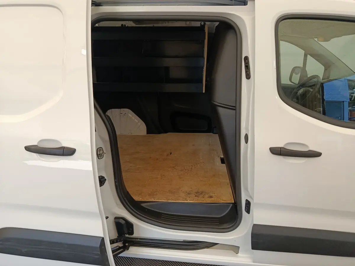 Vue latérale gauche d’un Citroën Berlingo blanc 2022 avec porte coulissante ouverte montrant l’espace de chargement en bois.