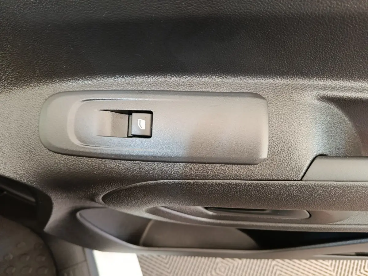 Gros plan sur le bouton de commande de la vitre électrique côté conducteur du Citroën Berlingo blanc, intérieur noir.