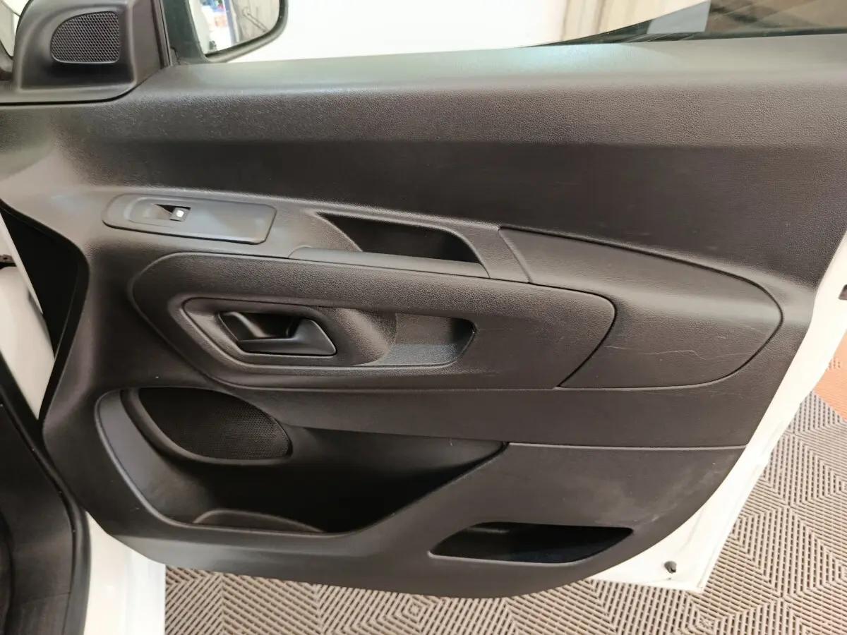 Vue rapprochée de la porte avant gauche noire du Citroën Berlingo blanc, montrant la poignée et les commandes de vitre.